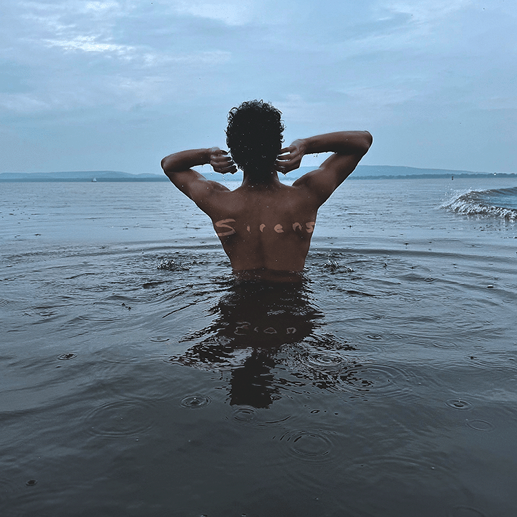Cover art of Zion Luna’s single “Sirens” featuring Zion Luna standing in water with arms raised